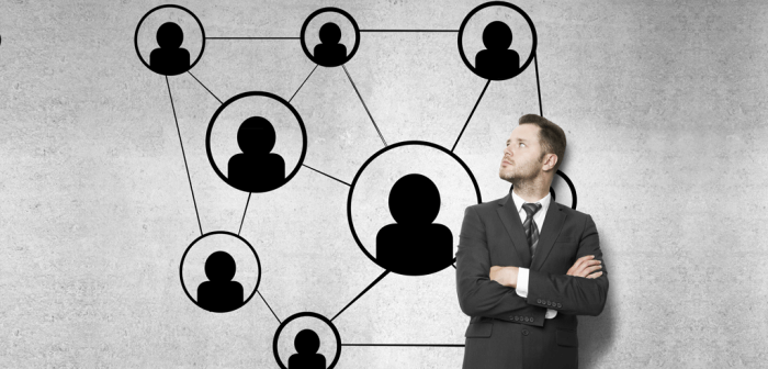 Businessman observing network of connected user icons on a wall.